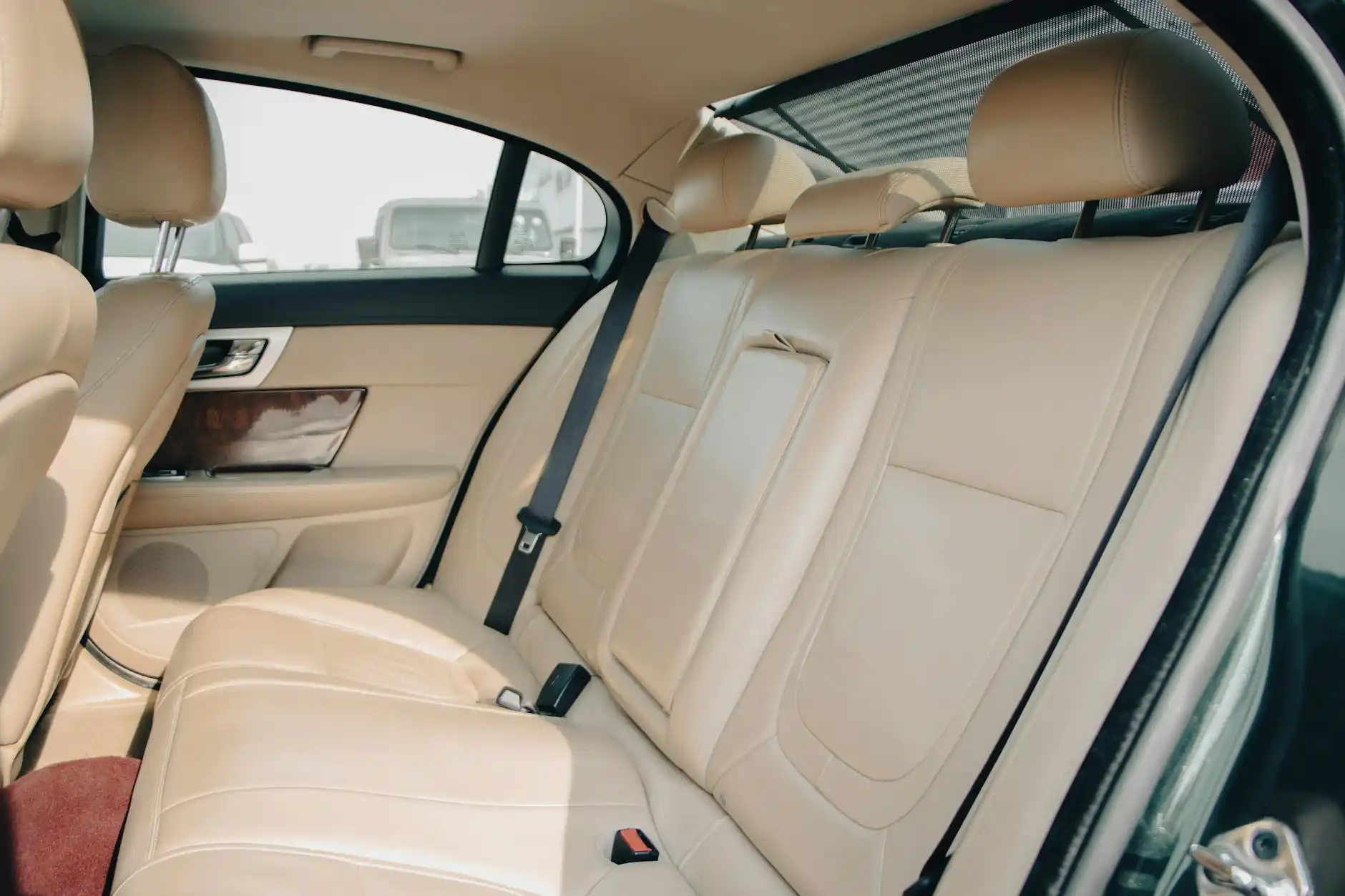 elegant interior of a premium executive sedan with tan leather seats, bottled water, phone charging ports, and Seattle skyline blurred through rain-speckled windows