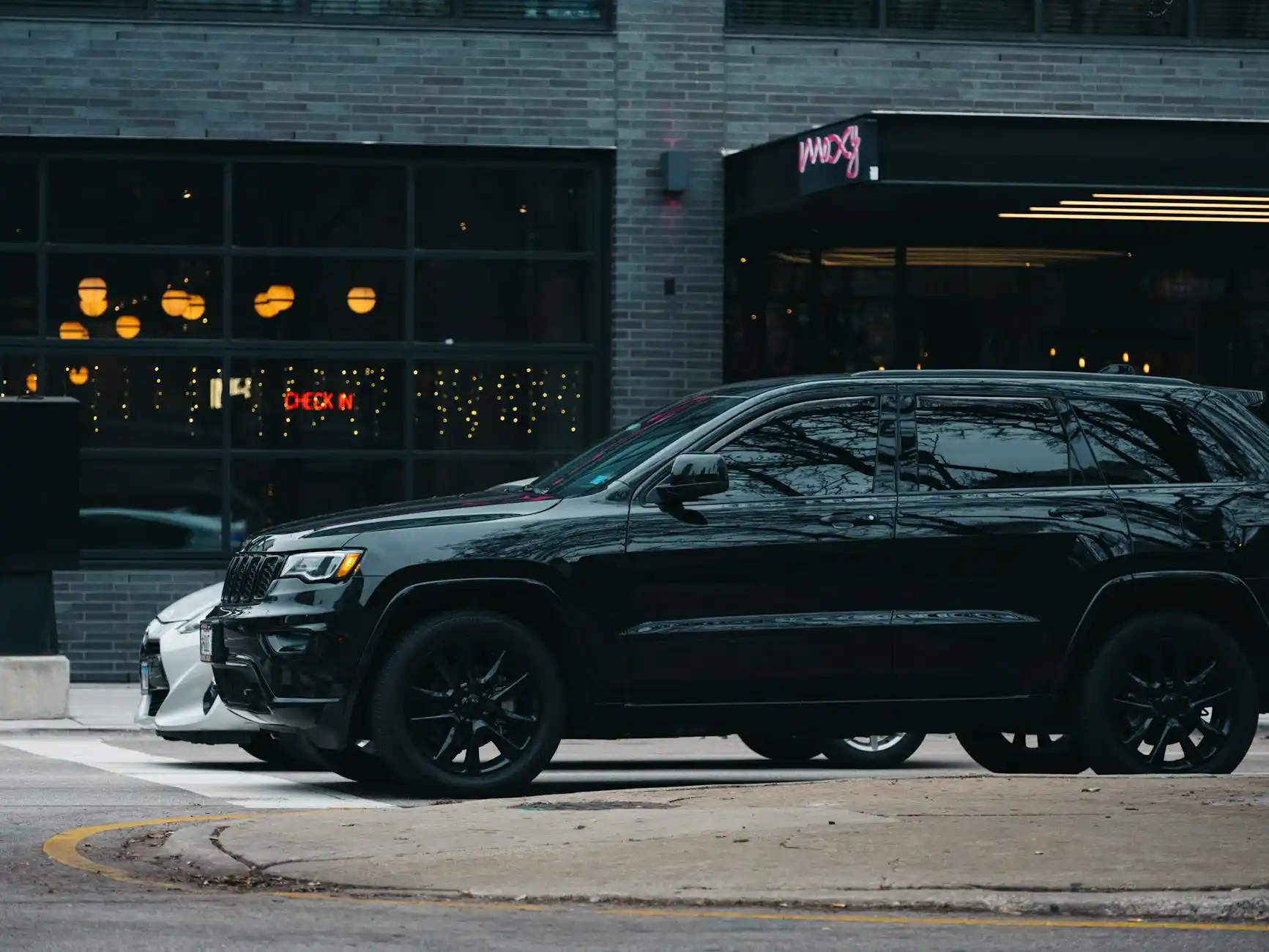 Seattle airport curbside pickup scene with a suited chauffeur holding a tablet, black SUV parked nearby, business traveler exiting terminal with carry-on luggage at golden hour