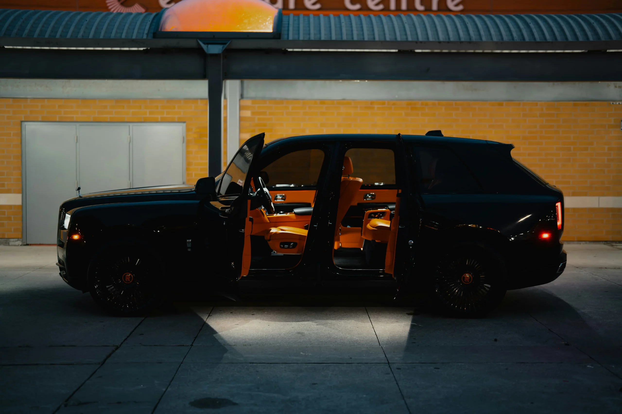 black luxury SUV limo pulling up to a decorated Seattle hotel entrance at dusk, holiday lights glowing, wet pavement reflecting city lights, Space Needle faintly visible in back...