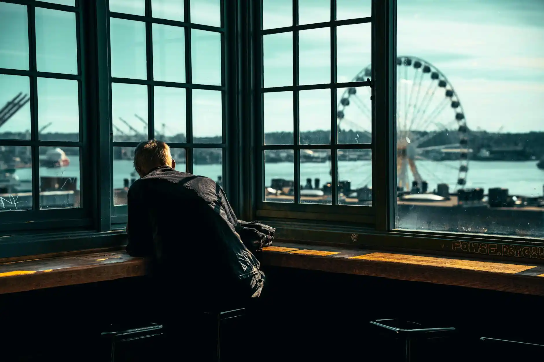 close-up of a traveler comparing limousine company reviews on a laptop in a Seattle hotel lobby, coffee cup, skyline visible through large windows