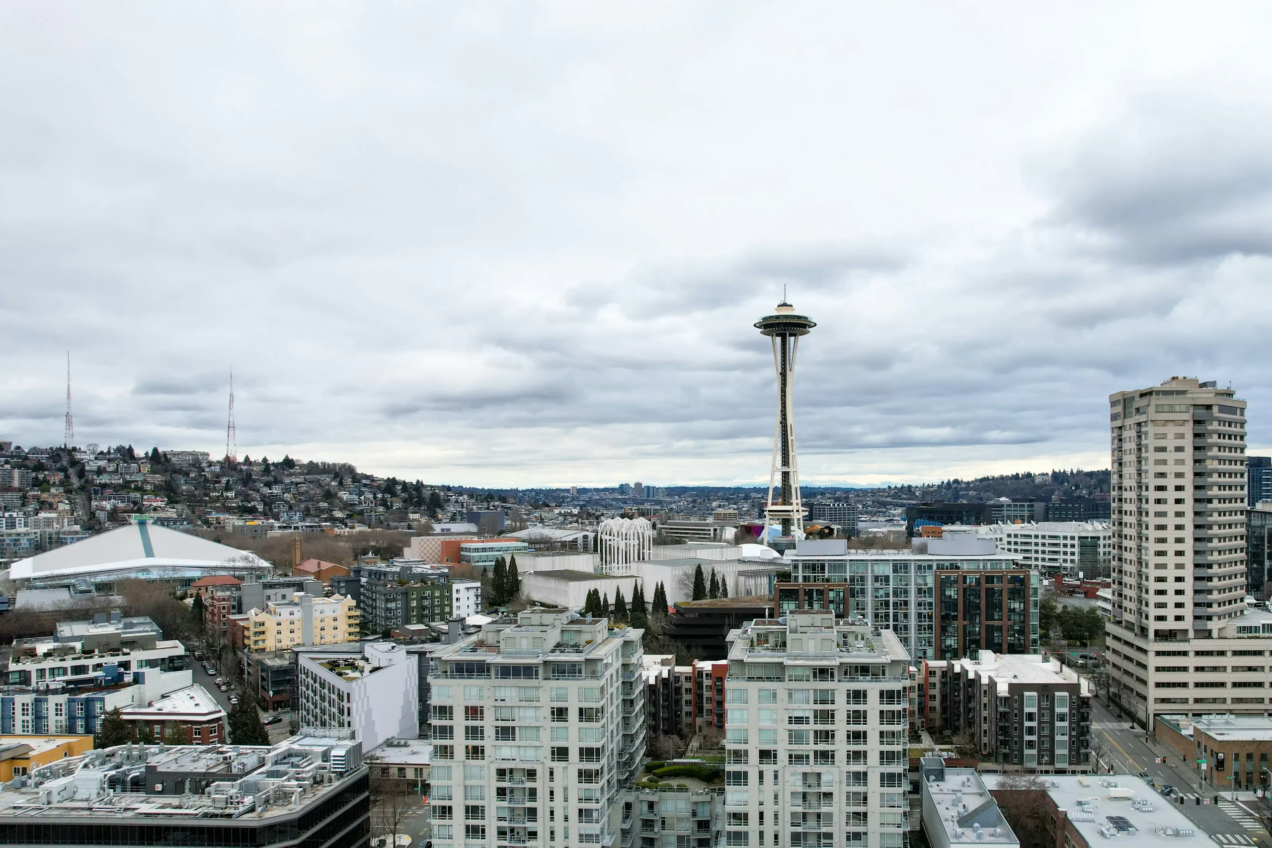 executive assistant in a modern Seattle office confirming lunch transportation on laptop, city skyline visible through windows, black town car waiting below at curb