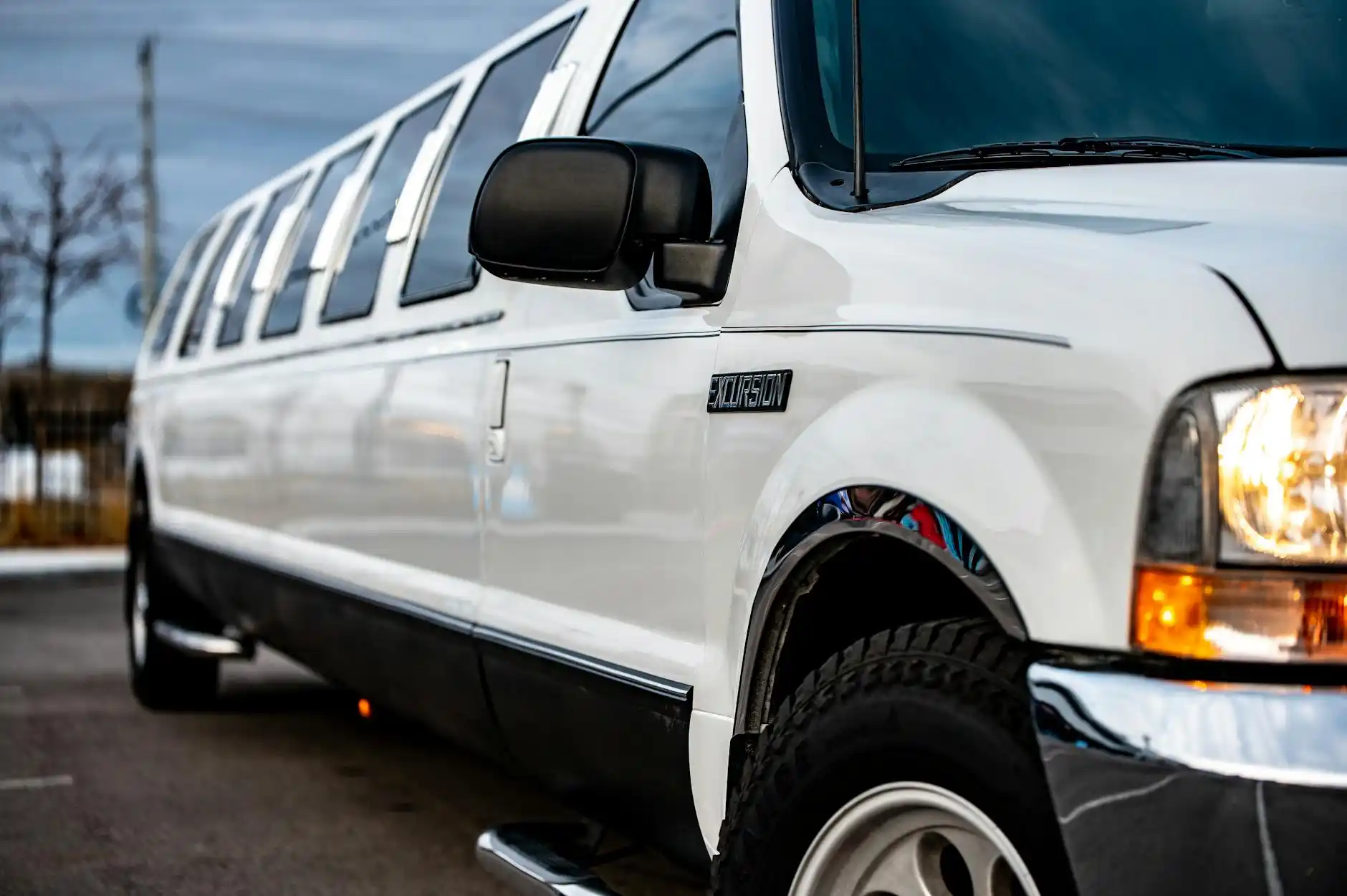 black luxury stretch limousine parked curbside in downtown Seattle at dusk, city lights reflecting on wet pavement, Space Needle faintly visible in the background