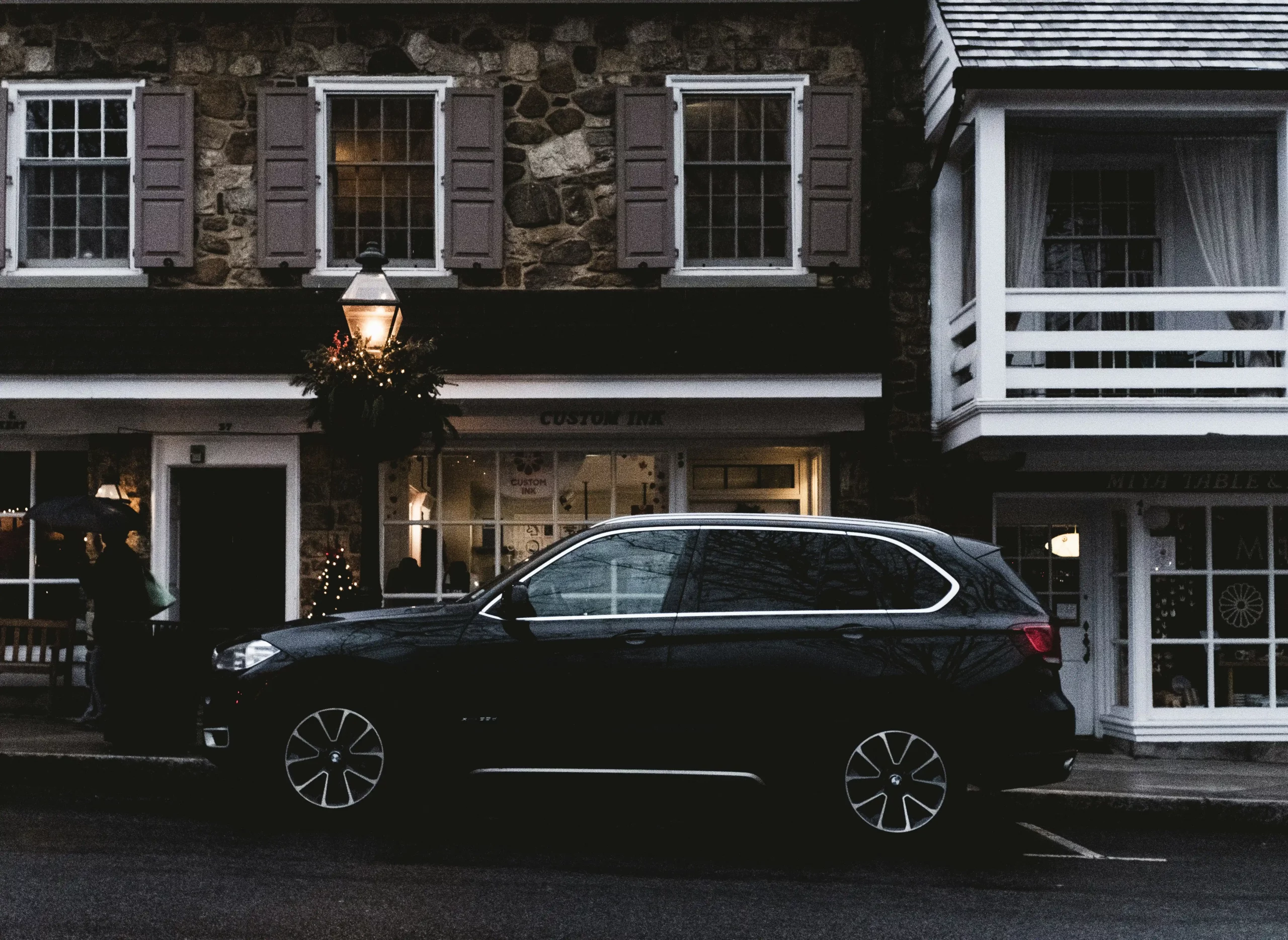 luxury black SUV and executive van parked outside a downtown Seattle hotel entrance, bell staff with luggage carts, glass high-rise reflections, early morning business travel at...