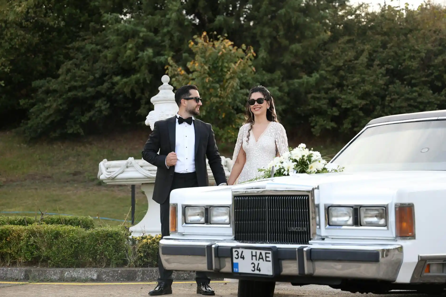 wedding couple entering a white stretch limousine outside a historic Seattle venue, floral arrangements, evening string lights, guests smiling in formal attire