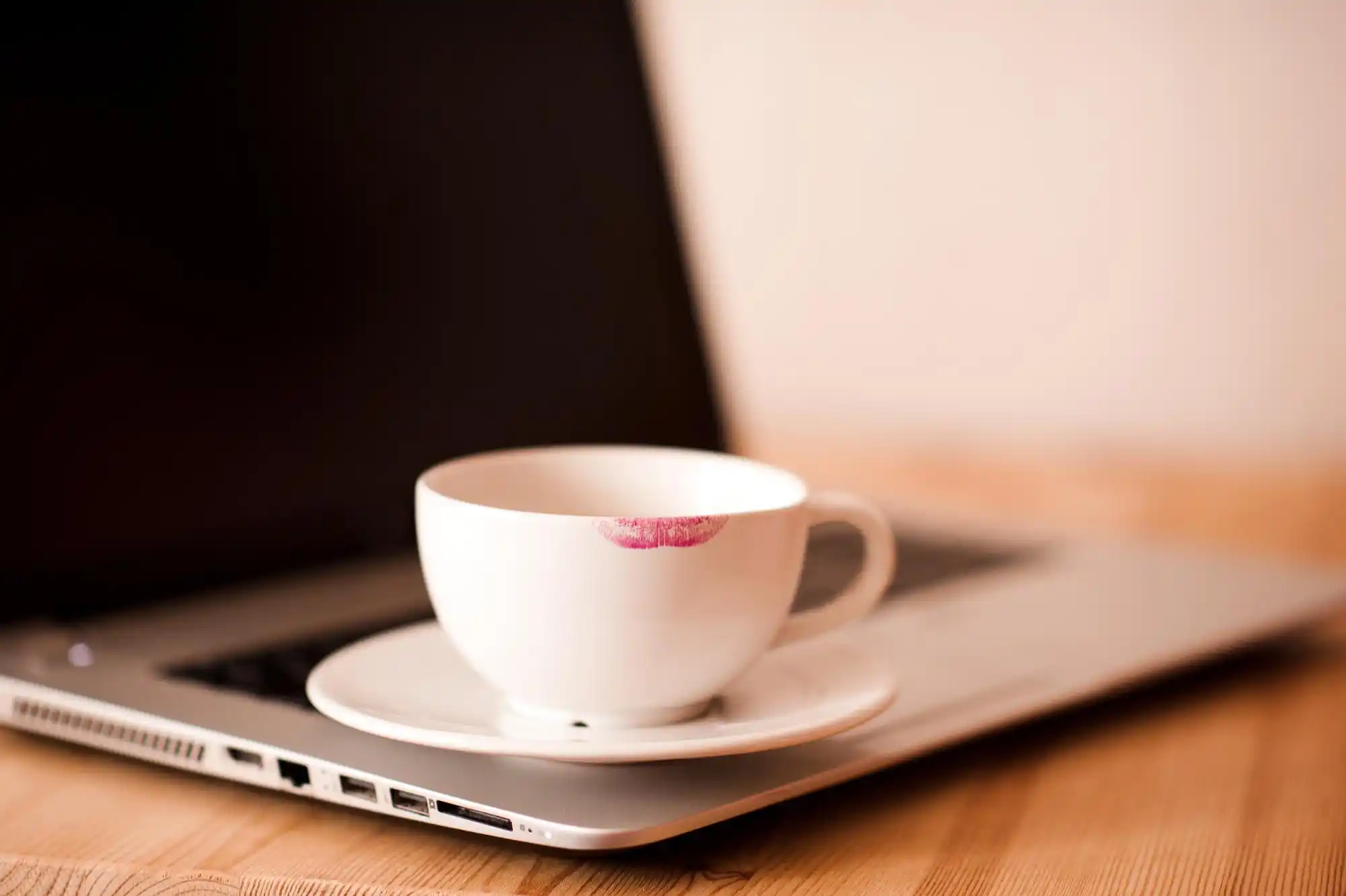close-up of laptop displaying luxury transportation booking confirmation beside smartphone with chauffeur text message, coffee cup on sleek office desk overlooking Seattle skyline