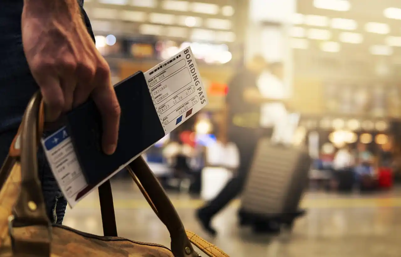 professional chauffeur opening the rear door of a black SUV for a business traveler outside Seattle-Tacoma International Airport, rolling suitcase and terminal signage in view
