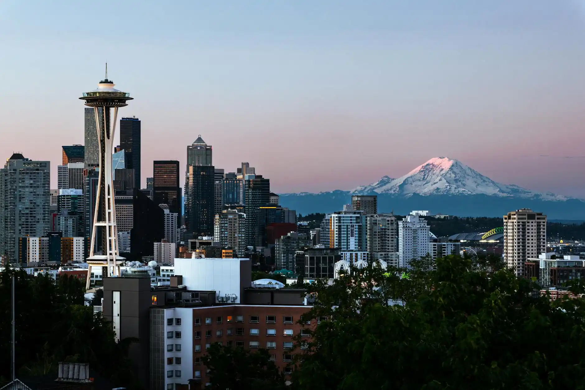 tourists overlooking Seattle skyline from Kerry Park at golden hour, black luxury SUV waiting curbside, Mount Rainier faintly visible in distance
