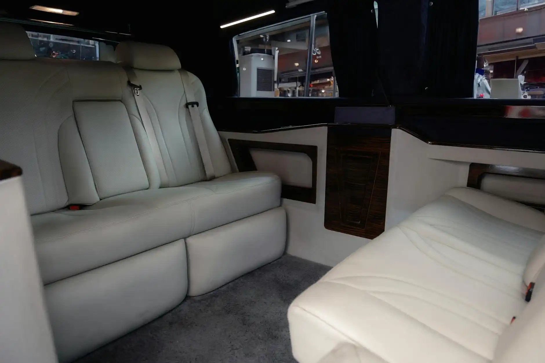 upscale Sprinter van interior with leather captain chairs, ambient lighting, tinted windows, bottled water, and Seattle game-day guests in business casual attire