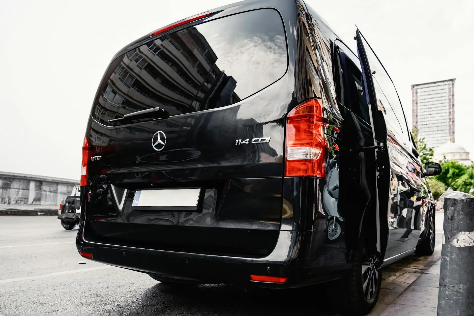 Seattle family and corporate guests boarding executive Sprinter van outside luxury hotel, baseball caps and business attire mixed, luggage neatly loaded in rear cargo area